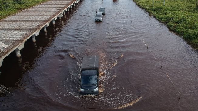 Foto udara pengendara mobil berusaha menerobos banjir yang merendam di jalan trans Kalimantan Bukit Rawi, Pulang Pisau, Kalimantan Tengah, Kamis (23/9/2021).  ANTARA FOTO/Makna Zaezar