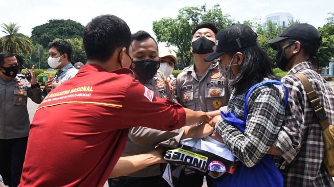 Polisi mengamankan demonstran dari Front Perjuangan Rakyat saat melakukan aksi tolak monopoli tanah dan pangan di depan Istana Negara, Jakarta, Kamis (23/9/2021).  ANTARA FOTO/Indrianto Eko Suwarso