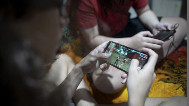 Ilustrasi gamers bermain Free Fire di smartphone. [Mauro Pimentel/AFP]
