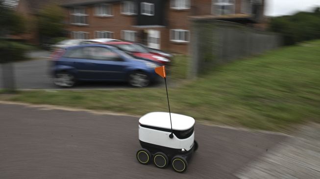 Sebuah robot otonom bernama Starship mengantarkan bahan makanan dari supermarket Co-op di Milton Keynes, Inggris, pada (20/9/2021). [DANIEL LEAL-OLIVAS / AFP]