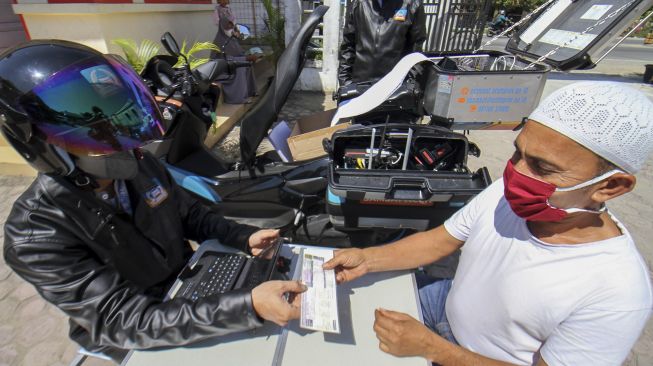 Petugas Samsat melayani pembayaran pajak kendaraan warga melalui fasilitas sepeda motor Sijempol di Desa Panggoi, Lhokseumawe, Aceh, Jumat (24/9/2021). [ANTARA FOTO/Rahmad]