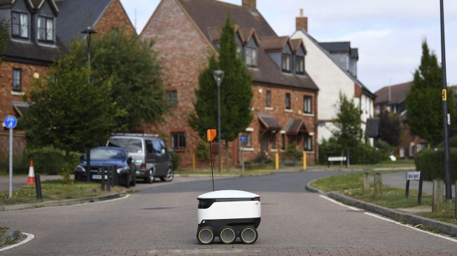 Sebuah robot otonom bernama Starship mengantarkan bahan makanan dari supermarket Co-op di Milton Keynes, Inggris, pada (20/9/2021). [DANIEL LEAL-OLIVAS / AFP]