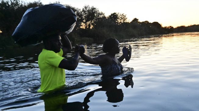 Migran Haiti menyeberangi Sungai Rio Grande di perbatasan Meksiko-AS, pada (23/9/2021). [PEDRO PARDO / AFP]