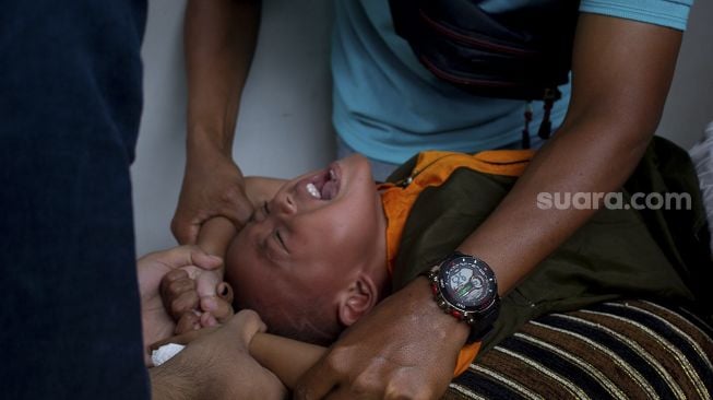 Ekspresi seorang anak saat mengikuti sunatan massal yang digelar di Binong Permai, Kabupaten Tangerang, Banten, Sabtu (25/9/2021). [Suara.com/ Hilal Rauda Fiqry]