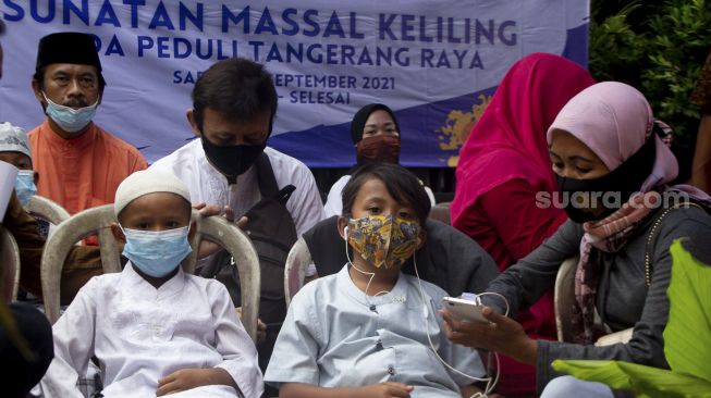 Sejumlah anak didampingi orang tuanya mengantre untuk mengikuti sunatan massal yang digelar di Binong Permai, Kabupaten Tangerang, Banten, Sabtu (25/9/2021). [Suara.com/ Hilal Rauda Fiqry]