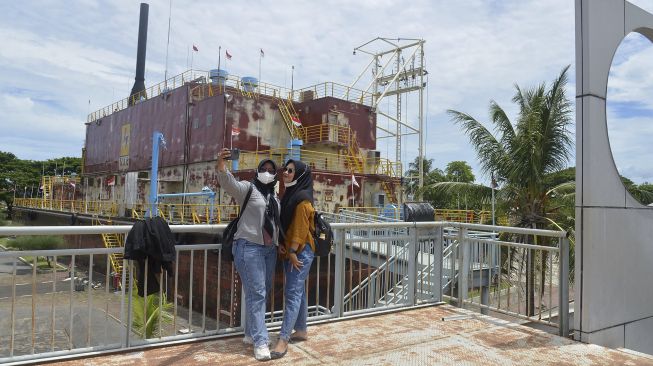 Wisatawan melakukan swafoto saat mengunjungi objek wisata Situs Tsunami Kapal PLTD Apung, di Desa Punge Blang Cut, Banda Aceh, Aceh, Sabtu (25/9/2021). [ANTARA FOTO/Ampelsa]