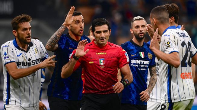 Pemain Inter dan Atalanta berdebat dengan wasit Fabio Maresca (tengah) selama pertandingan sepak bola Serie A Italia antara Inter Milan melawan Atalanta di Giuseppe Meazza, Sabtu (25/9/2021) malam WIB.  Marco BERTORELLO / AFP
