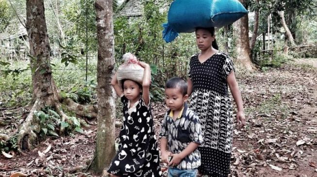 Warga Suku Ammatoa berjalan kaki tanpa memakai sandal di kawasan adat Ammatoa, Kabupaten Bulukumba, Sulawesi Selatan [SuaraSulsel.id / Lorensia Clara Tambing]