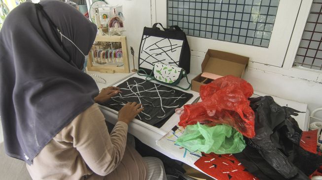 Perajin membuat produksi tas dari kantong plastik bekas di Anda Craft, Sawangan, Depok, Jawa Barat, Minggu (26/9/2021).  ANTARA FOTO/Asprilla Dwi Adha
