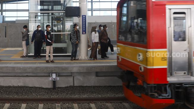 Penumpang menunggu kereta Commuterline di Jalur Layang Bogor Line Stasiun Manggarai, Jakarta Selatan, Minggu (26/9/2021). [Suara.com/Alfian Winanto]