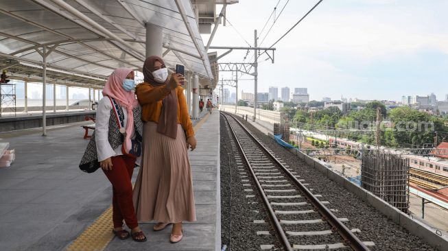 Penumpang berswafoto di Jalur Layang Bogor Line Stasiun Manggarai, Jakarta Selatan, Minggu (26/9/2021). [Suara.com/Alfian Winanto]