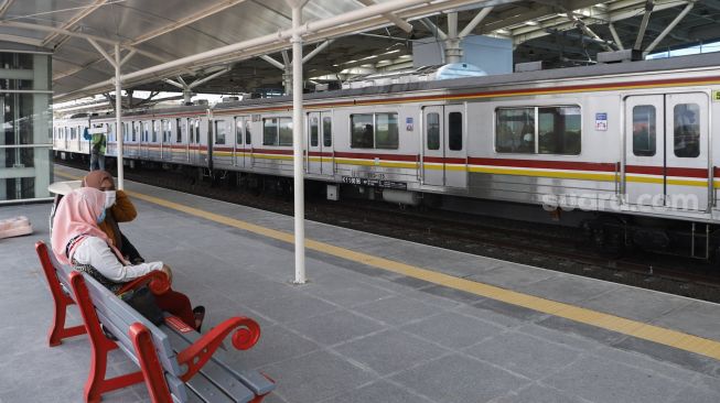 Penumpang menunggu kereta Commuterline di Jalur Layang Bogor Line Stasiun Manggarai, Jakarta Selatan, Minggu (26/9/2021). [Suara.com/Alfian Winanto]