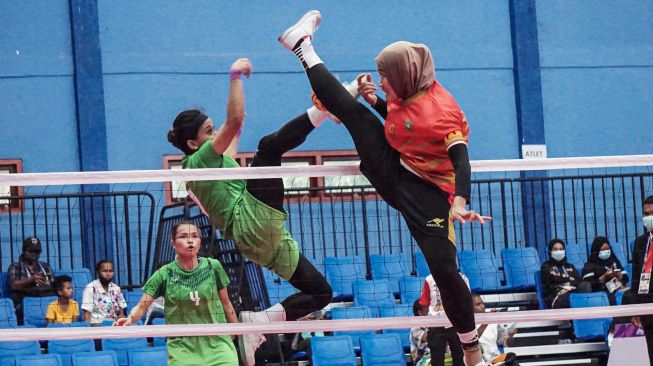 Atlet sepak takraw putri Riau Nurhidayah (kanan) berupaya menangkis bola yang dilepaskan atlet sepak takraw putri Jawa Timur Avlia Febriani (tengah) dalam pertandingan sepak takraw ganda putri PON Papua, di GOR Trikora Universitas Cenderawasih, Jayapura, Papua, Senin (27/9/2021). ANTARA FOTO/Indrayadi TH
