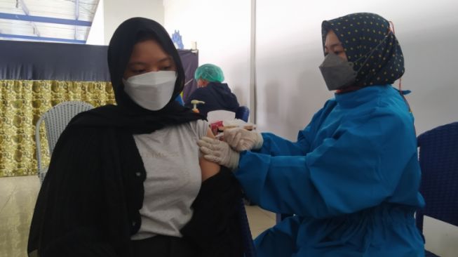 Seorang warga mengikuti kegiatan vaksinasi Covid-19 di Objek Wisata Floating Market, Lembang, Kabupaten Bandung Barat pada Senin (27/9/2021). [Suara.com/Ferrye Bangkit Rizki]