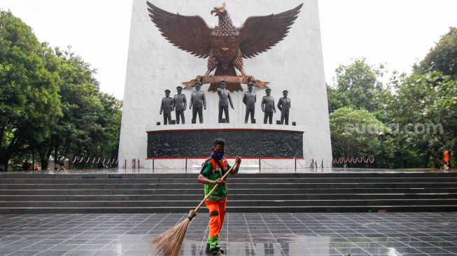 Petugas membersihkan area Tugu Pahlawan Revolusi di Monumen Pancasila Sakti, Lubang Buaya, Jakarta Timur, Selasa (28/9/2021). [Suara.com/Alfian Winanto]