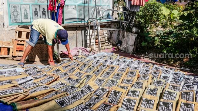 Pekerja menjemur sajadah yang sudah di sablon di Kawasan Tanah Abang, Jakarta Pusat, Rabu (29/9/2021). [Suara.com/Alfian Winanto]