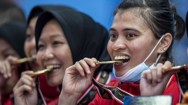 Sejumlah pesepak takraw putri DKI Jakarta menggigit medali emasnya pada upacara pengalungan medali usai pertandingan final ganda putri beregu Sepak Takraw PON Papua melawan Jawa Timur di GOR Trikora Universitas Cenderawasih, Jayapura, Papua, Rabu (29/9/2021).  ANTARA FOTO/M Risyal Hidayat
