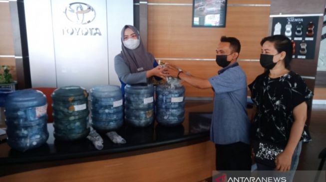 Pasangan suami istri Asriadi Syamsuddin dan Ratna saat menyerahkan galon dan kardus berisi uang receh untuk pembelian Toyota Rush di Kota Makassar [ANTARA/Darwin Fatir].