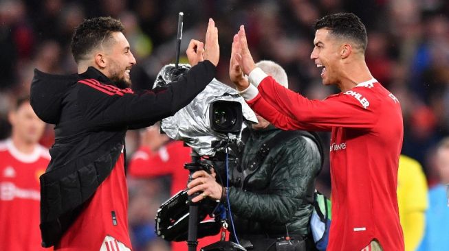 Penyerang Manchester United, Cristiano Ronaldo (kanan) dan Alex Telles merayakan kemenangan timnya atas Villarreal di matchday kedua Grup F Liga Champions di Old Trafford, Kamis (30/9/2021) dini hari WIB. Anthony Devlin / AFP.