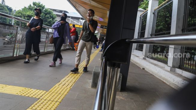 Warga melintas di Halte Stasiun Palmerah, Jakarta Pusat, Kamis (30/9/2021). [Suara.com/Alfian Winanto]