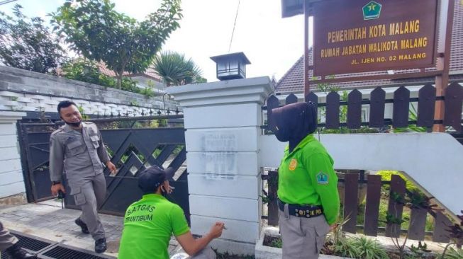 Penghapusan vandalisme di marka jalan simpang empat Rajabally, Kota Malang, Jumat (1/10/2021). [Suara.com/Bob Bimantara Leander]