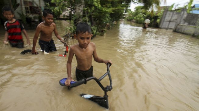 Sejumlah anak mendorong keluar sepeda dari rendaman banjir di Desa Blang Priya, Kecamatan Samudera Geudong, Aceh Utara, Aceh, Jumat (1/10/2021). [ANTARA FOTO/Rahmad]