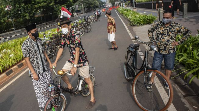 Anggota Komunitas Onthel Batavia berbaju batik saat bersepeda di kawasan Bundaran HI, Jakarta, Sabtu (2/10/2021). [ANTARA FOTO/Aprillio Akbar]