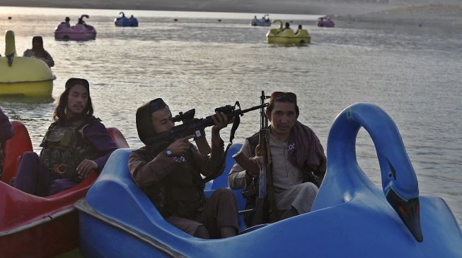 Pejuang Taliban menaiki perahu dayung di sebuah taman bermain di Danau Qargha, Kabul, Afghanistan, pada (28/9/2021). [WAKIL KOHSAR / AFP]