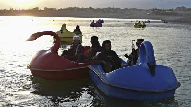 Pejuang Taliban menaiki perahu dayung di sebuah taman bermain di Danau Qargha, Kabul, Afghanistan, pada (28/9/2021). [WAKIL KOHSAR / AFP]