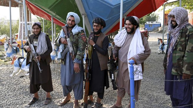 Para pejuang Taliban berdiri di samping wahana komidi putar di sebuah taman bermain di Danau Qargha, Kabul, Afghanistan, pada (28/9/2021). [WAKIL KOHSAR / AFP]
