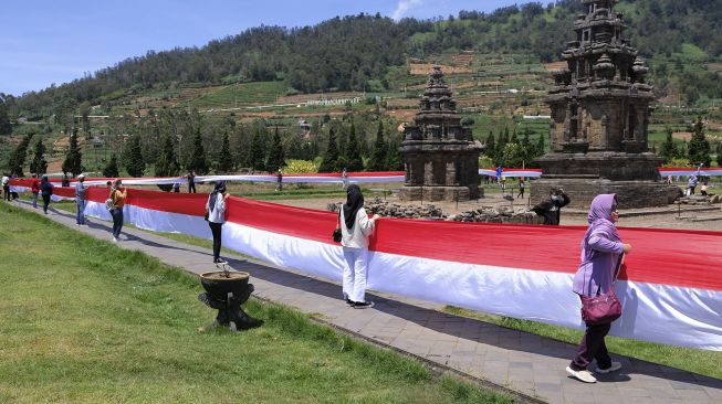 Peserta membentangkan Bendera Merah Putih saat peringatan Hari Kesaktian Pancasila di kompleks Candi Arjuna dataran tinggi Dieng, Batur, Banjarnegara, Jateng, Jumat (1/10/2021). [ANTARA FOTO/Anis Efizudin]