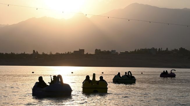 Pejuang Taliban menaiki perahu dayung di sebuah taman bermain di Danau Qargha, Kabul, Afghanistan, pada (28/9/2021). [WAKIL KOHSAR / AFP]