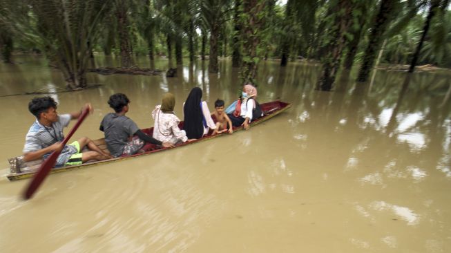 Warga menggunakan perahu keluar dari kepungan banjir di Desa Hagu, Kecamatan Matang Kuli, Aceh Utara, Aceh, Jumat (1/10/2021). [ANTARA FOTO/Rahmad]