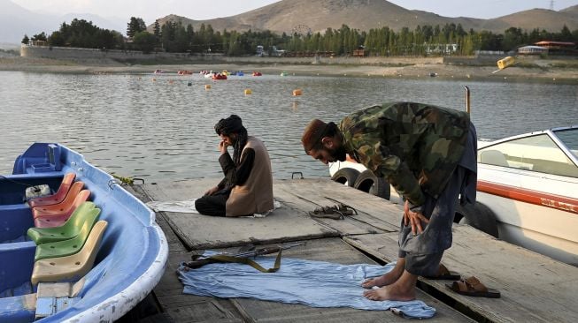 Pejuang Taliban berdoa di sebuah taman bermain di Danau Qargha, Kabul, Afghanistan, pada (28/9/2021). [WAKIL KOHSAR / AFP]