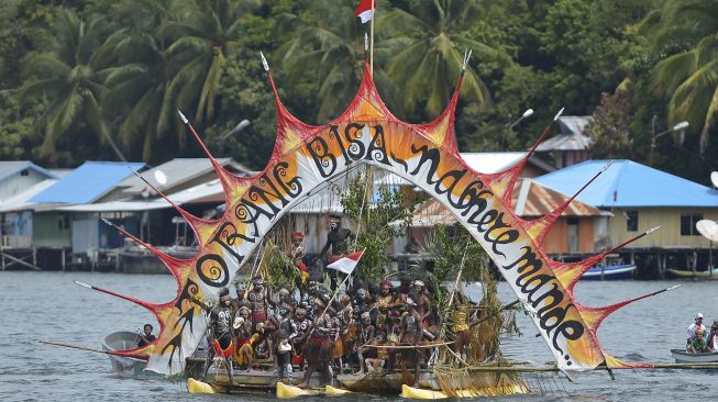 Sejumlah warga dengan pakaian adat menggunakan perahu saati kirab api PON tiba di Dermaga Kalkhote, Danau Sentani, Kabupaten Jayapura, Papua, Sabtu (2/10/2021). [ANTARA FOTO/Fauzan]