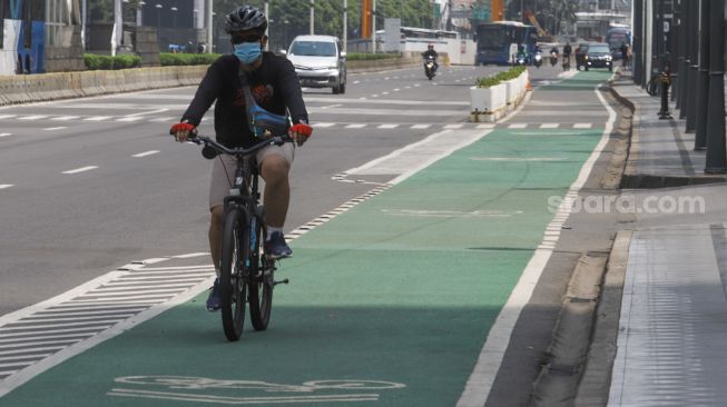 Warga berolahraga di jalan Jenderal Sudirman, Jakarta Pusat, Minggu (3/10/2021). [Suara.com/Alfian Winanto]