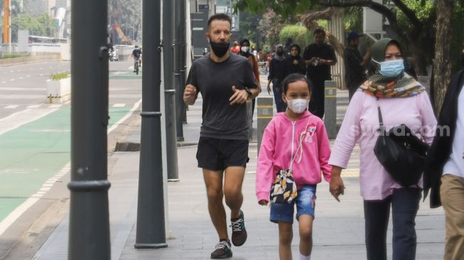 Warga berolahraga di jalan Jenderal Sudirman, Jakarta Pusat, Minggu (3/10/2021). [Suara.com/Alfian Winanto]