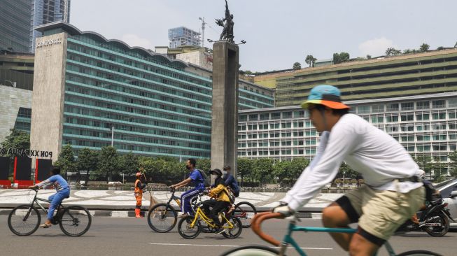 Warga berolahraga di kawasan Bundaran Hotel Indonesia (HI), Jakarta Pusat, Minggu (3/10/2021). [Suara.com/Alfian Winanto]