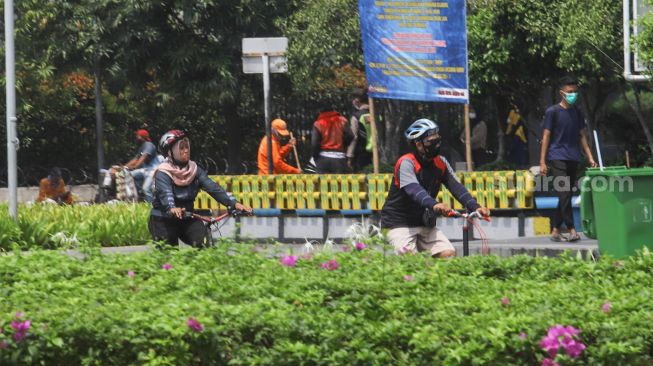 Warga berolahraga di kawasan Bundaran Hotel Indonesia (HI), Jakarta Pusat, Minggu (3/10/2021). [Suara.com/Alfian Winanto]