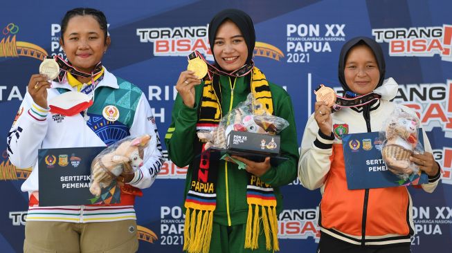 Atlet panahan Jawa Timur Diananda Choirunisa (tengah), atlet panahan Papua Rezza Octavia (kiri) dan atlet Kalimantan Tengah Linda Lestari (kanan) berpose dengan medalinya di podium saat upacara penyerahan medali final panahan recurve putri PON Papua di Lapangan Kampung Harapan, Sentani, Kabupaten Jayapura, Papua, Senin (4/10/2021).ANTARA FOTO/Zabur Karuru
