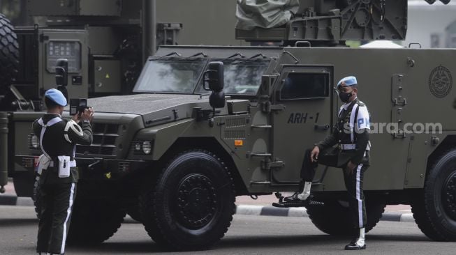 Personel Polisi Militer berfoto di dekat alutsista yang terparkir di depan Istana Merdeka, Jakarta, Senin (4/10/2021). [Suara.com/Angga Budhiyanto]