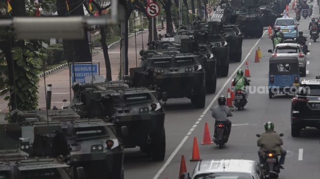 Sejumlah kendaraan melintas di dekat deretan alutsista yang terparkir di kawasan Patung Kuda Arjuna Wiwaha, Jakarta, Senin (4/10/2021). [Suara.com/Angga Budhiyanto]