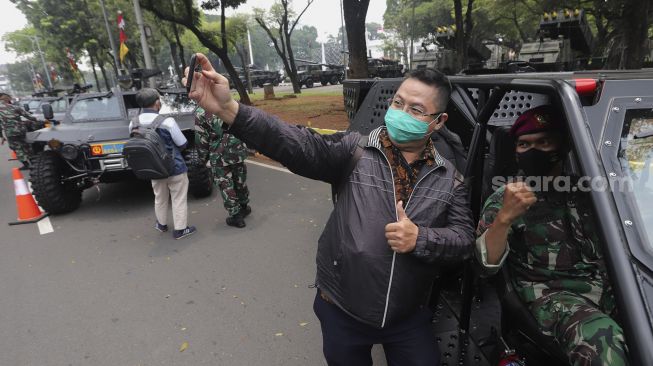 Warga berswafoto bersama prajurit TNI saat pameran alutsista di depan Istana Merdeka, Jakarta, Senin (4/10/2021). [Suara.com/Angga Budhiyanto]