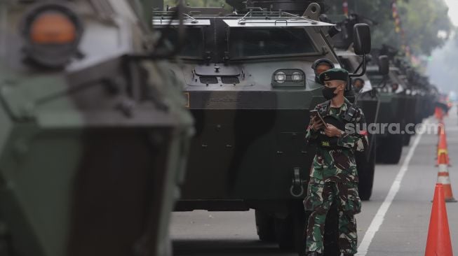 Prajurit TNI berjalan di dekat deretan alutsista yang terparkir di kawasan Patung Kuda Arjuna Wiwaha, Jakarta, Senin (4/10/2021). [Suara.com/Angga Budhiyanto]