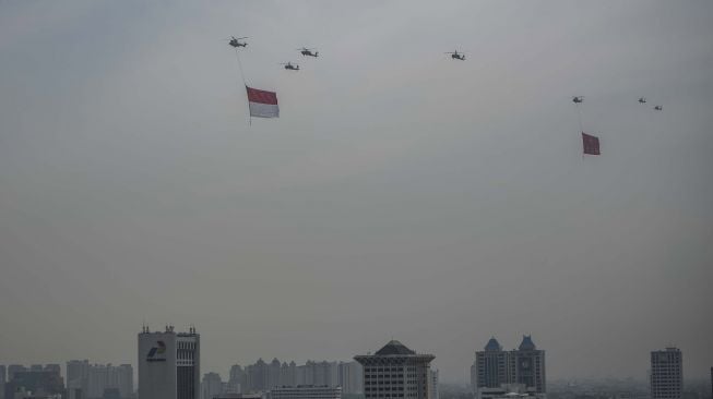 Tujuh helikopter TNI terbang dengan mengibarkan bendera Merah Putih dan Lambang TNI di kawasan Monas, Jakarta, Selasa (5/10/2021). ANTARA FOTO/Aprillio Akbar