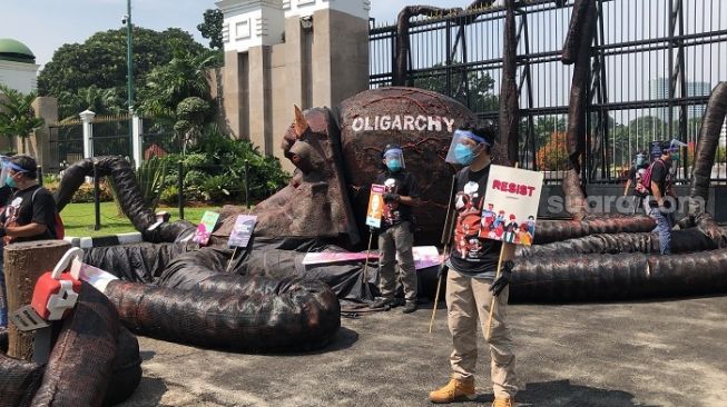 Aktivis Greenpeace berujuk rasa samberi membawa "Monster Oligarki" di depan gedung DPR. (Suara.com/Novian)