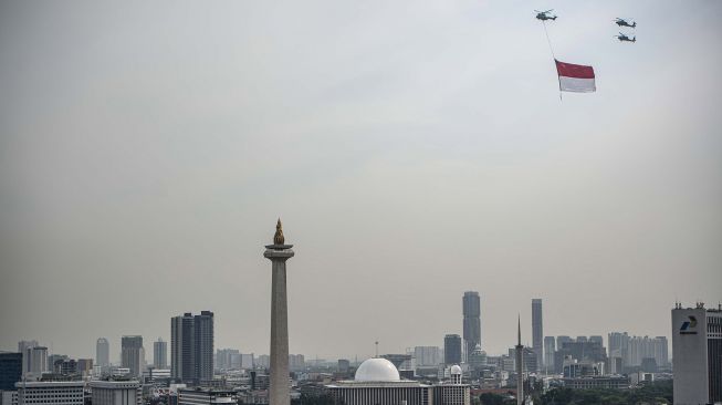 Tiga helikopter TNI terbang dengan mengibarkan bendera Merah Putih di kawasan Monas, Jakarta, Selasa (5/10/2021). ANTARA FOTO/Aprillio Akbar