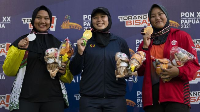 Atlet Jawa Barat Tresna Puspita (tengah), atlet Riau Indah Pratiwi (kiri), dan atlet DKI Jakarta Syarina Priandani (kanan) berpose dengan medali usai bertanding dalam final nomor lontar martil putri PON Papua di Stadion Atletik Mimika Sport Center, Kabupaten Mimika, Papua, Rabu (6/10/2021).  ANTARA FOTO/Aditya Pradana Putra