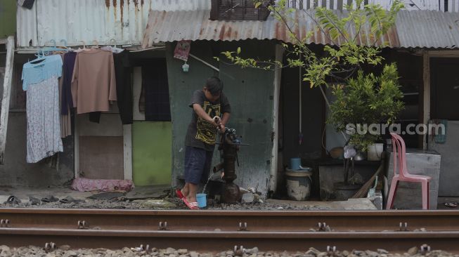 Seorang anak memompa air tanah di kawasan Petamburan, Jakarta, Rabu (6/10/2021). [Suara.com/Angga Budhiyanto]