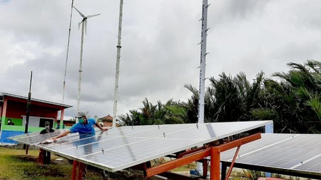 Pengurus PLTH saat membersihkan panel surya yang terpasang di Dusun Bondan, Desa Ujungalang, Kecamatan Kampunglaut, Kabupaten Cilacap, Rabu (6/10/2021). [ANTARA/Sumarwoto]